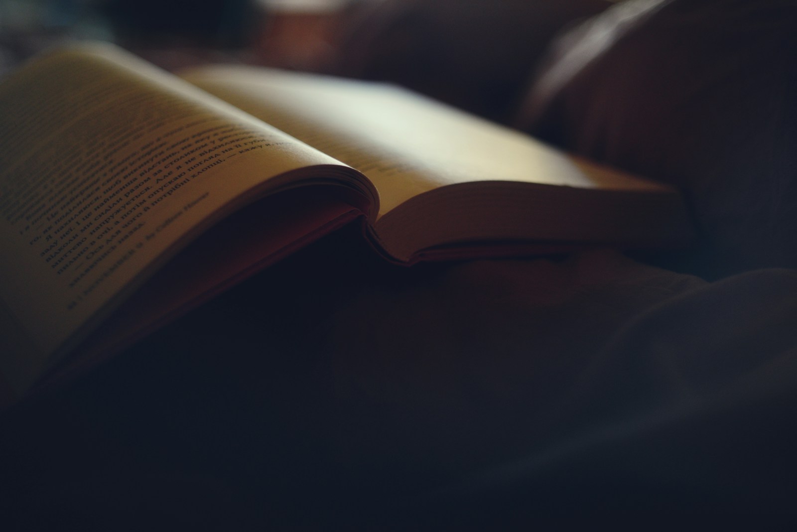 Still life with an open book, stacked books, and a small brass oil lamp in warm light